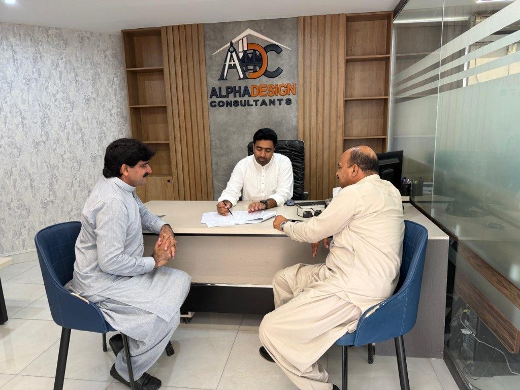 Consultation at the Managing Director's desk with the ADC logo wall behind